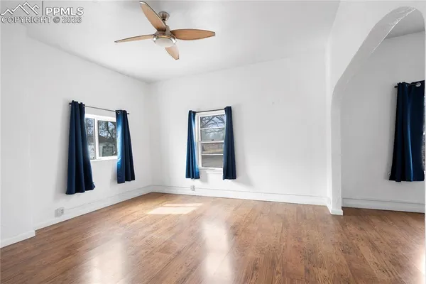 a view of an empty room with window and wooden floor