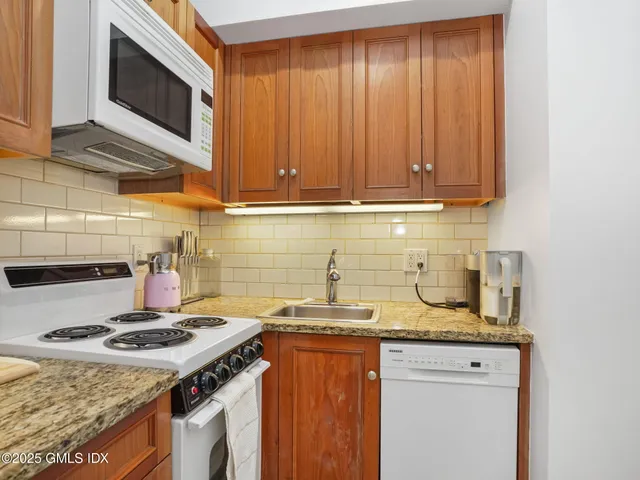 a kitchen with granite countertop a sink stove and cabinets