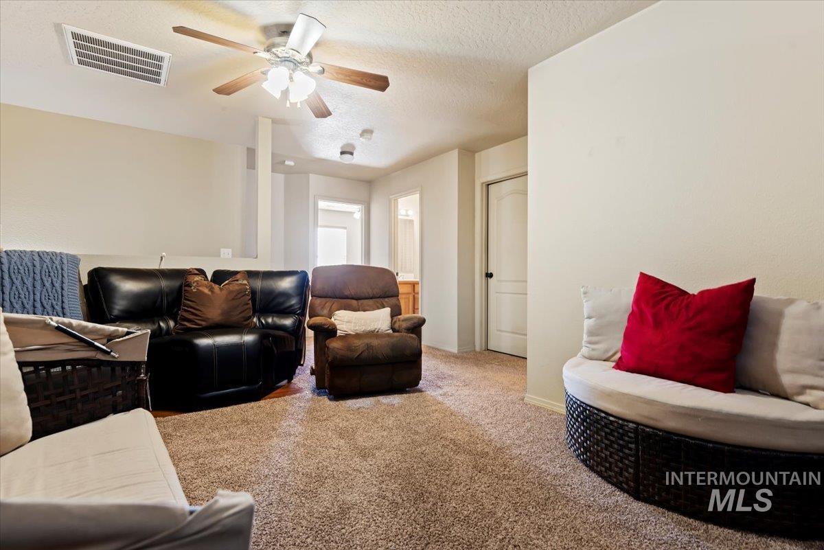 14057 Santa Cruz Street Caldwell, ID 83607 - Photo 13 of 26 Living area with carpet floors, a textured ceiling, and a ceiling fan