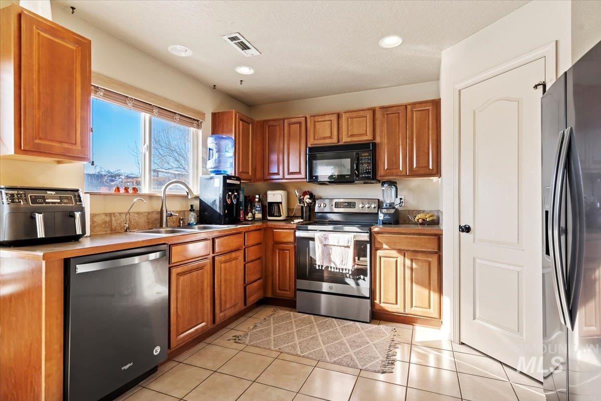 14057 Santa Cruz Street Caldwell, ID 83607 - Photo 9 of 26 Kitchen featuring black appliances, brown cabinets, light tile patterned floors, and recessed lighting