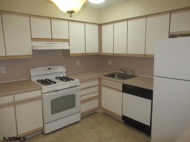4 Oyster Bay, Unit 4K Absecon, NJ 08201 - Photo 2 of 8 a kitchen with white cabinets and white appliances