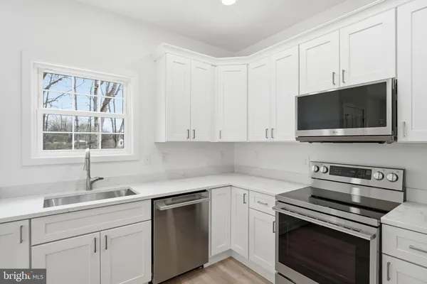 a kitchen with cabinets stainless steel appliances a sink and a window