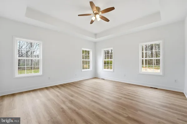 a view of empty room with wooden floor and fan
