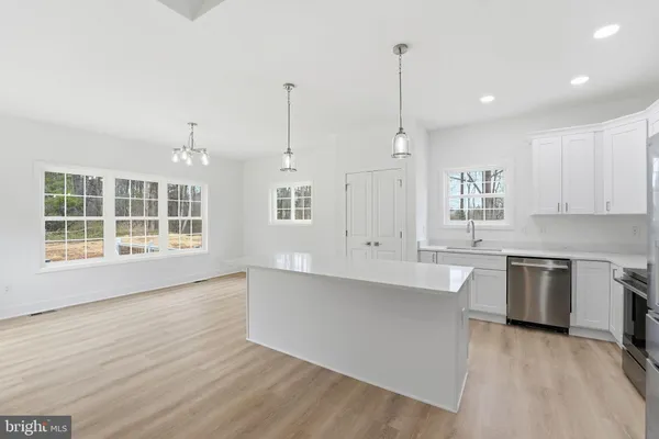 a large kitchen with granite countertop a stove a sink a center island and wooden floor