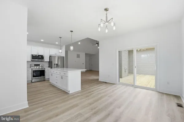 a large kitchen with kitchen island a stove a refrigerator a sink dishwasher with a dining table and wooden floor