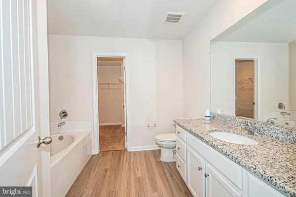 a bathroom with a granite countertop sink a toilet and a shower