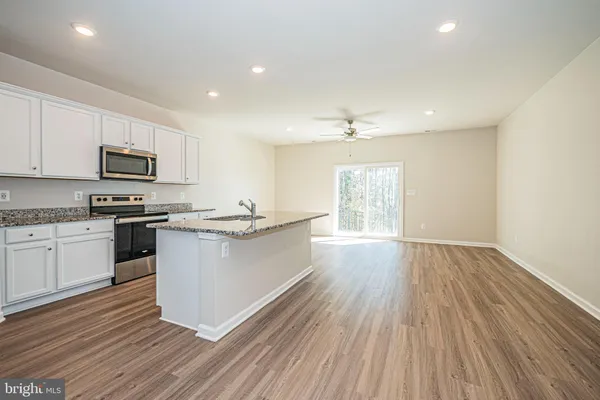 a kitchen with granite countertop wooden floors a stove top oven a sink and dishwasher with wooden floor