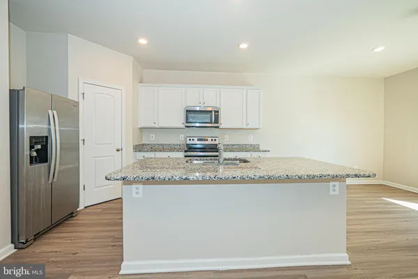 a kitchen with granite countertop a sink a refrigerator and a stove