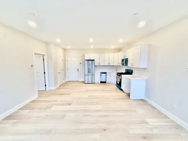 a large white kitchen with kitchen island a sink stainless steel appliances and cabinets