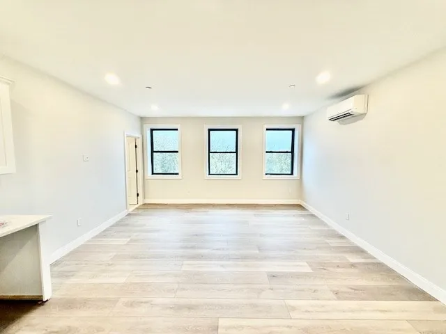 a view of an empty room with wooden floor and windows