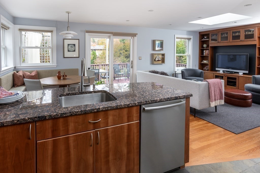 47 Arlington Road Brookline, MA 02467 - Photo 12 of 29 a kitchen with granite countertop a sink dishwasher a dining table and chairs with wooden floor