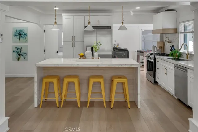 a kitchen with stainless steel appliances kitchen island a table chairs and a chandelier
