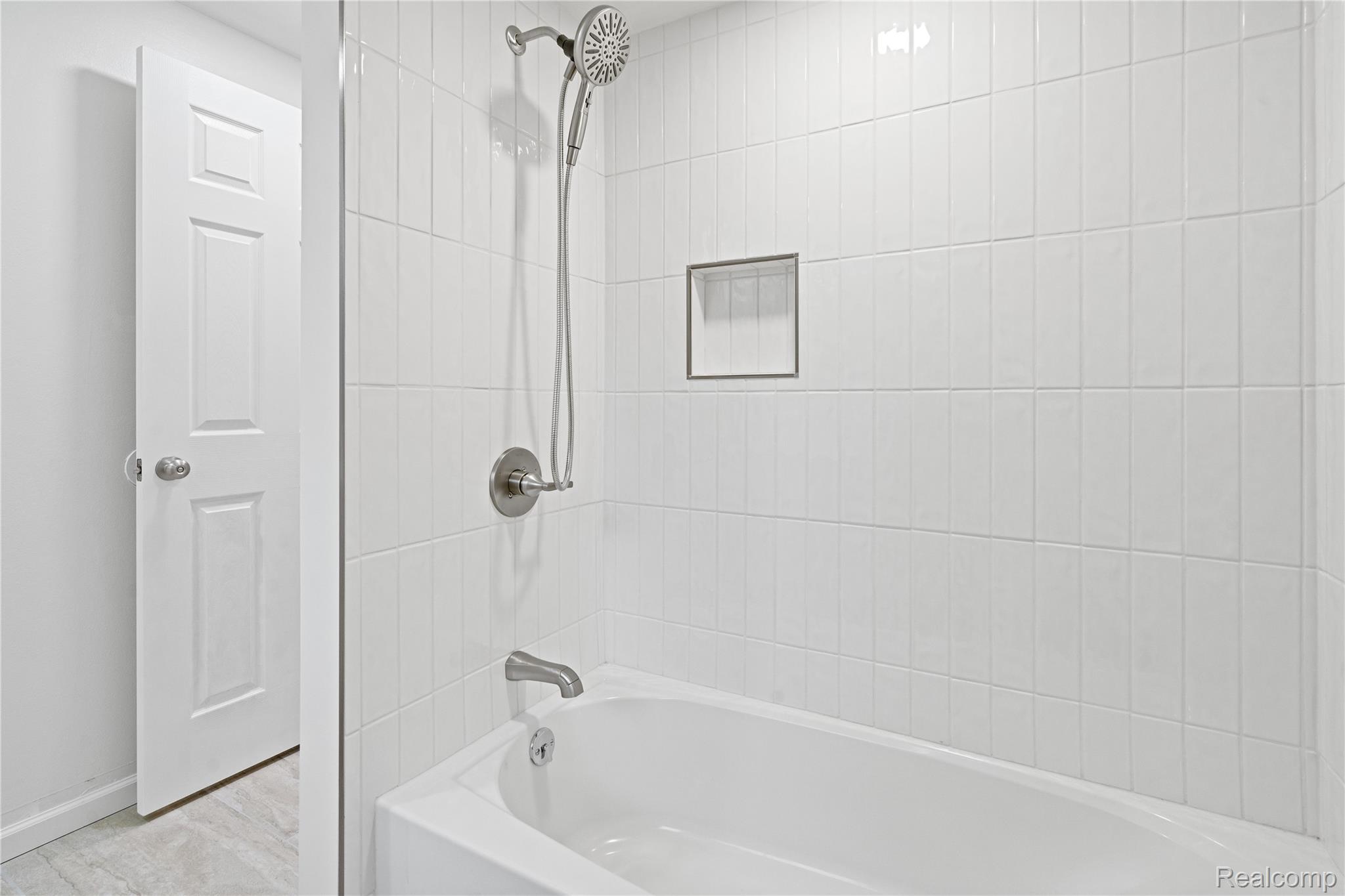 8240 Hampton Road Grosse Ile, MI 48138 - Photo 12 of 33 White subway tile shower surround with a built-in niche, chrome shower fixtures, and a white soaking tub