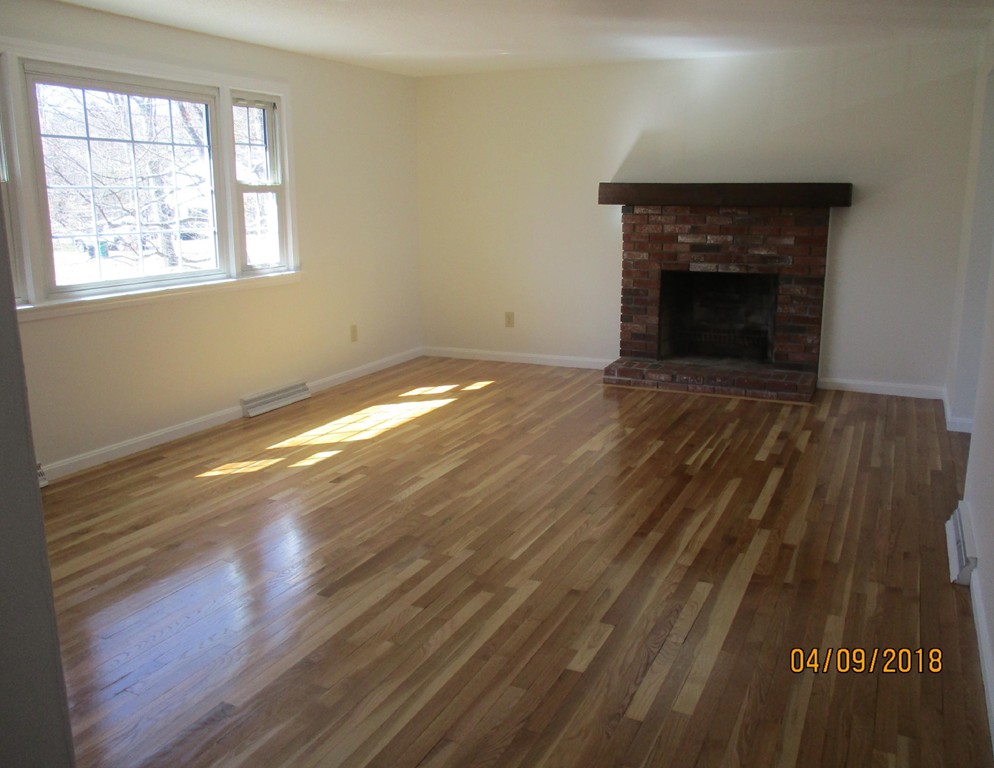 165 Swift Road Northbridge, MA 01588 - Photo 3 of 24 an empty room with wooden floor fireplace and windows