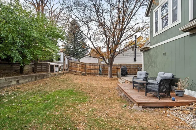 a view of a backyard with table and chairs potted plants and a large tree