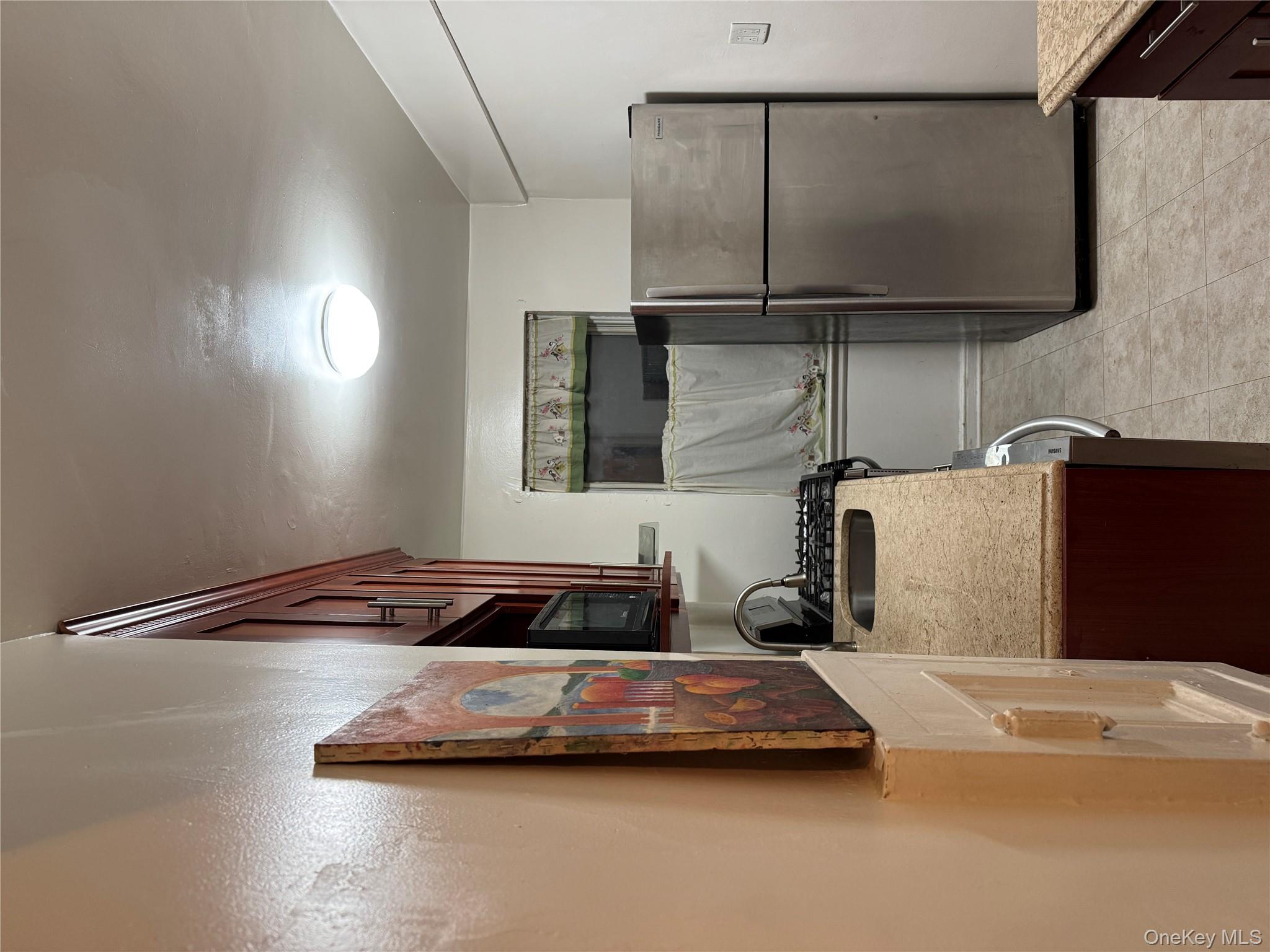 141-17 78th Road, Unit 1O Queens, NY 11367 - Photo 17 of 17 Kitchen with refrigerator, light stone countertops, light tile patterned floors, and dark brown cabinets