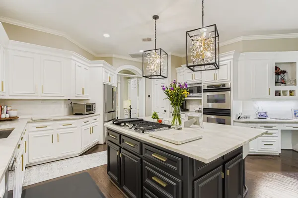 a kitchen with stainless steel appliances a stove a sink dishwasher a refrigerator and white cabinets with wooden floor