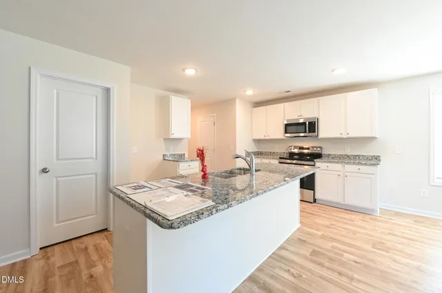 a view of a kitchen with kitchen island a sink wooden floor and a refrigerator