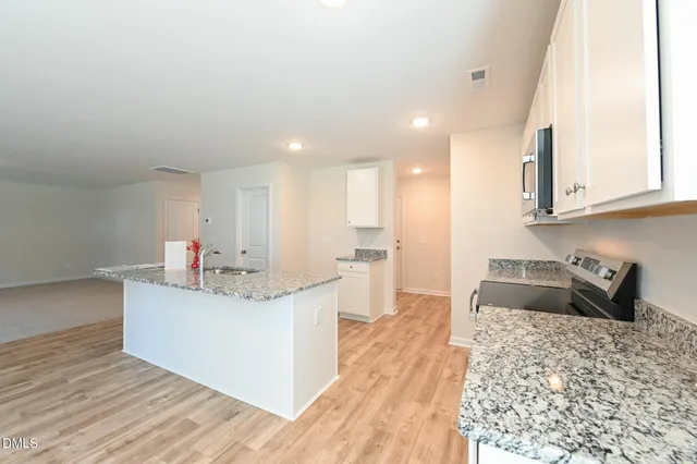 a kitchen with granite countertop a sink stove and refrigerator