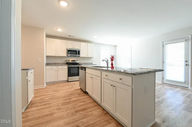a kitchen with granite countertop a stove a microwave and cabinets