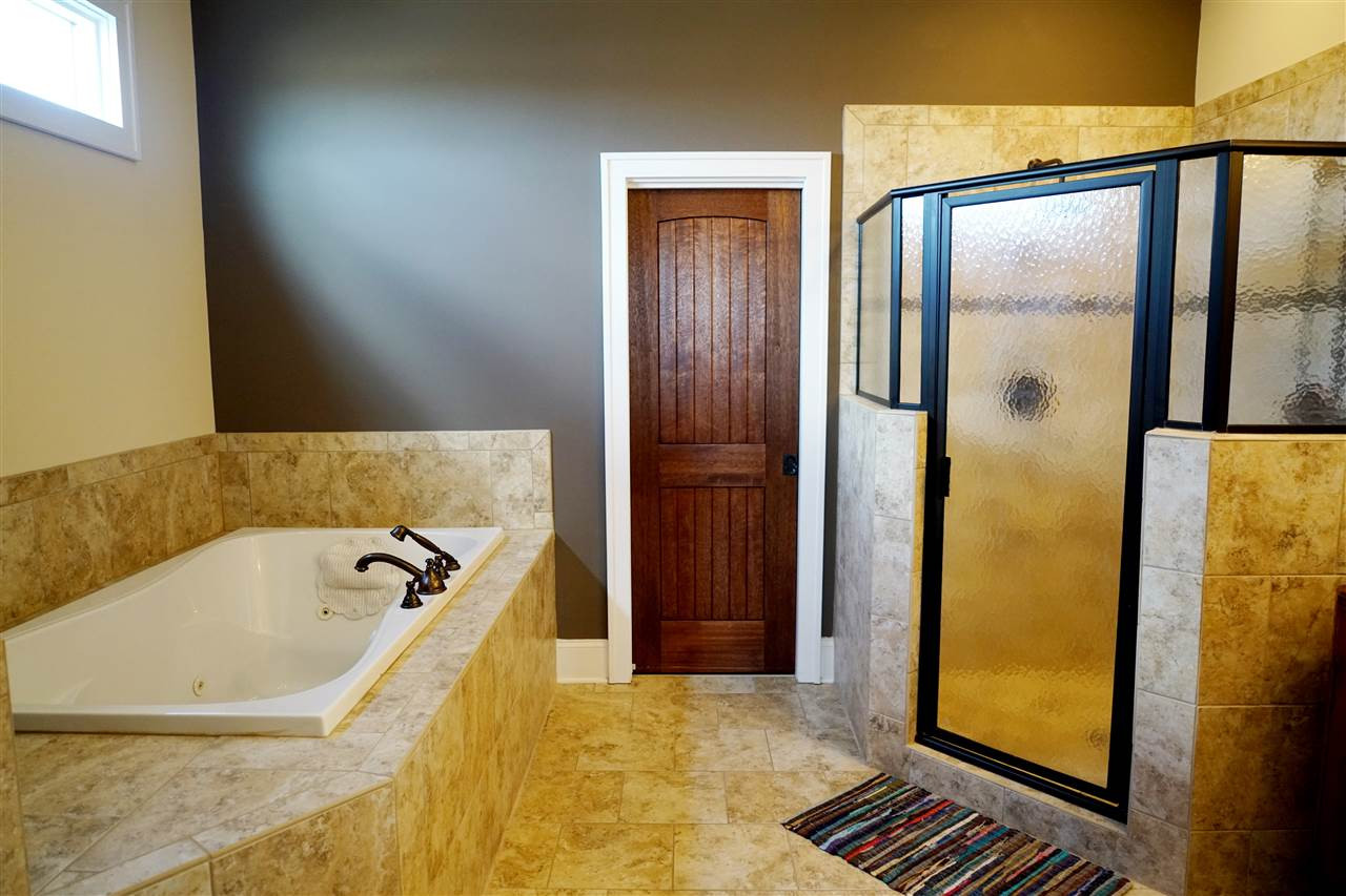 607 Competition Road Raleigh, NC 27603 - Photo 15 of 20 Master bath with large whirlpool, dual shower heads in shower, heated tile floor, door leading to walk-in closet