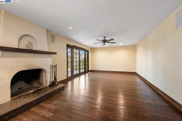 a view of an empty room with wooden floor fireplace and a window