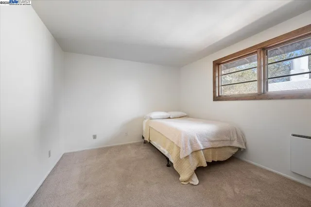a bedroom with a bed and next to a window