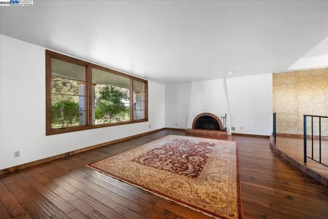 a view of a bedroom with wooden floor and window