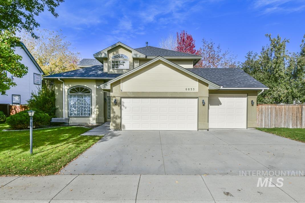 Traditional-style house with driveway, a garage, a shingled roof, and stucco siding