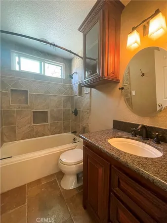 a bathroom with a granite countertop sink mirror toilet and bathtub