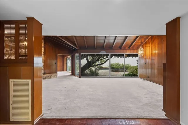 a view of an empty room with wooden floor and windows