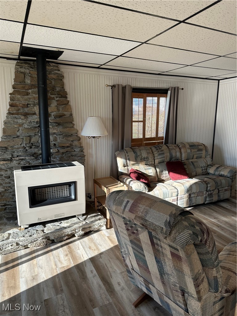 314 Devon Road Woodsfield, OH 43793 - Photo 24 of 50 Living room with a wood stove, heating unit, a drop ceiling, and wood finished floors