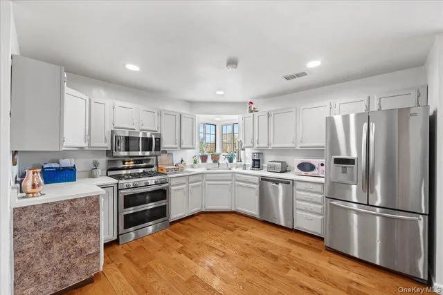 a kitchen with stainless steel appliances granite countertop a stove top oven a refrigerator a sink and dishwasher with wooden floor