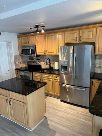 a kitchen with kitchen island granite countertop a sink cabinets and stainless steel appliances