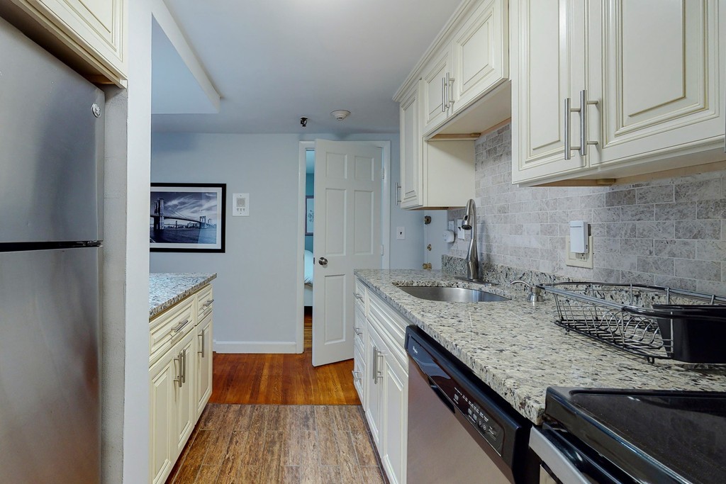 242 Beacon Street, Unit 2 Boston, MA 02116 - Photo 2 of 10 a kitchen with granite countertop stainless steel appliances and wooden cabinets