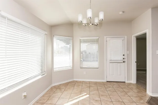 an empty room that has a window and chandelier