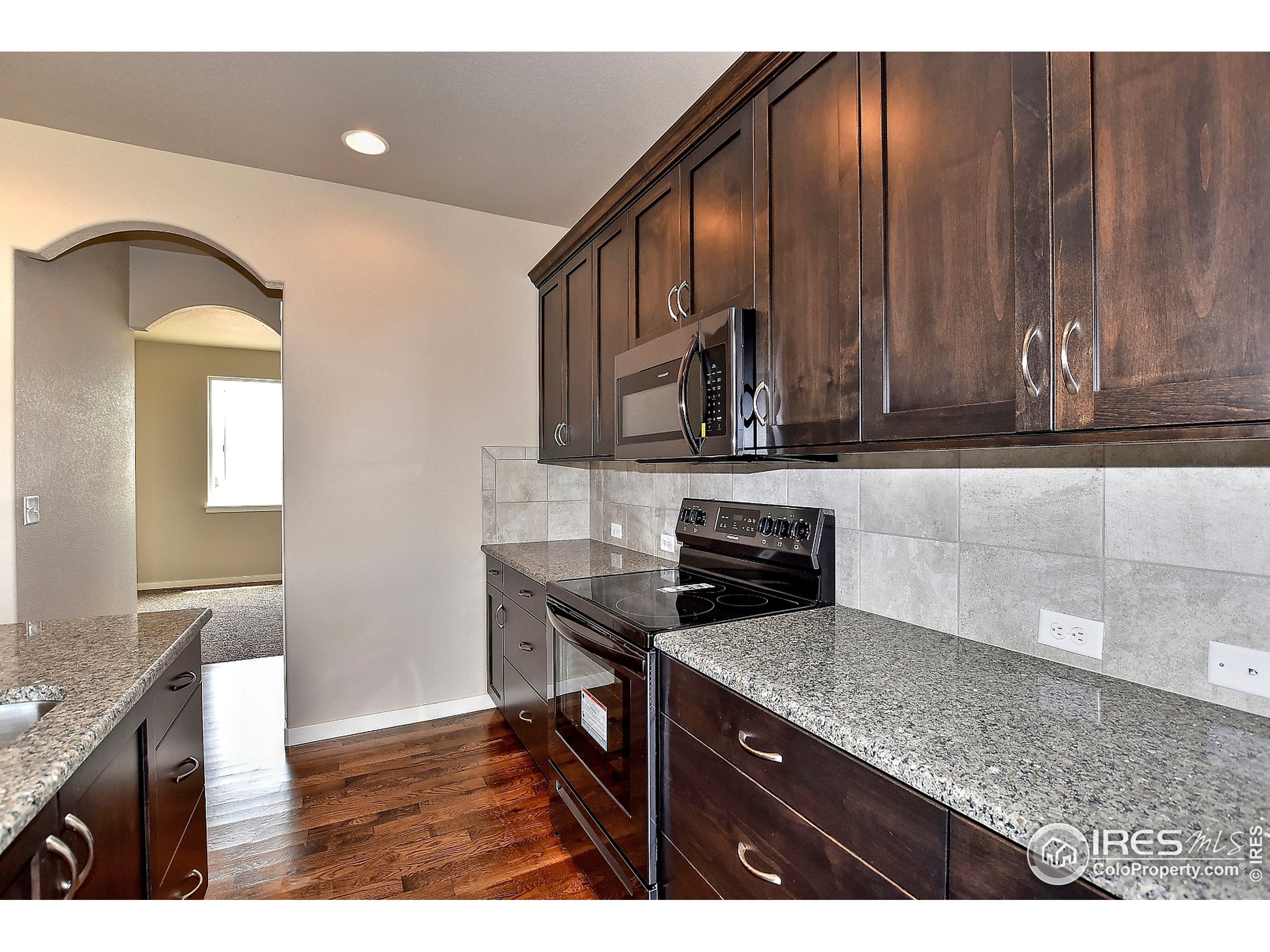 6630 Pebble Path Court Timnath, CO 80547 - Photo 12 of 18 a kitchen with stainless steel appliances granite countertop a stove a sink and a microwave