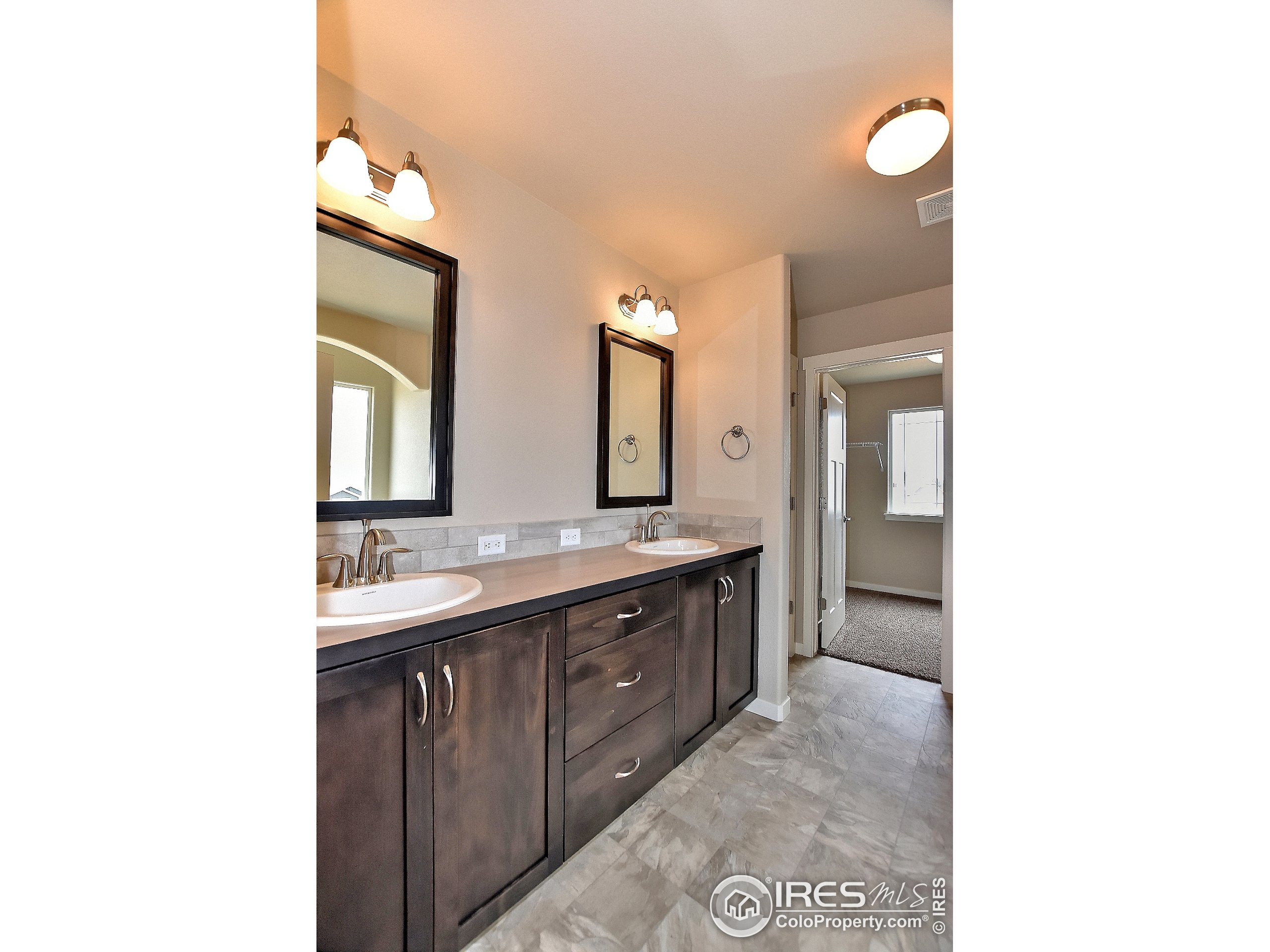 6630 Pebble Path Court Timnath, CO 80547 - Photo 13 of 18 a spacious bathroom with a double vanity sink and a mirror
