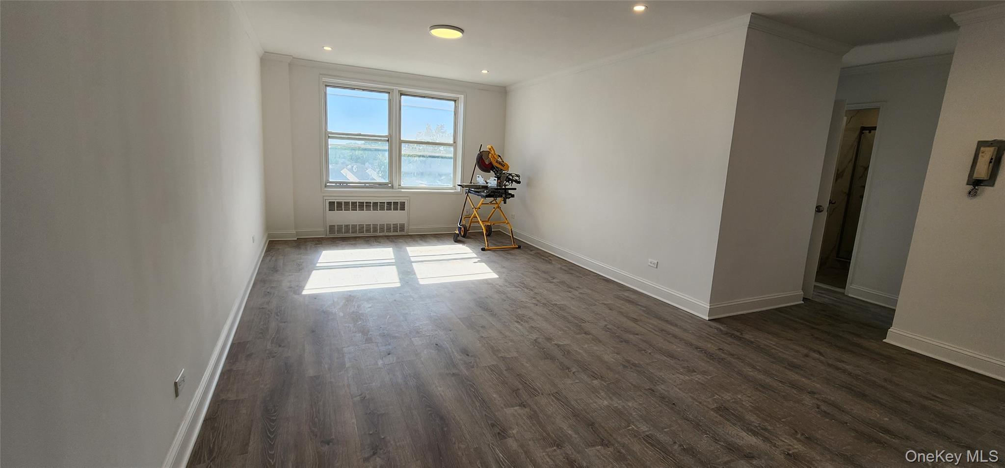 222-89 Braddock Avenue, Unit 5A Queens, NY 11428 - Photo 4 of 9 an empty room with wooden floor and windows