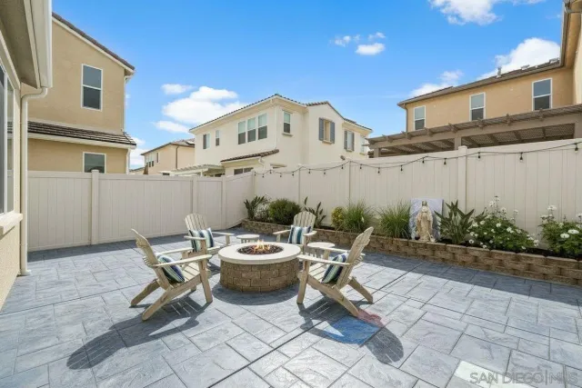 a view of a patio with a dining table and chairs with plants and wooden fence