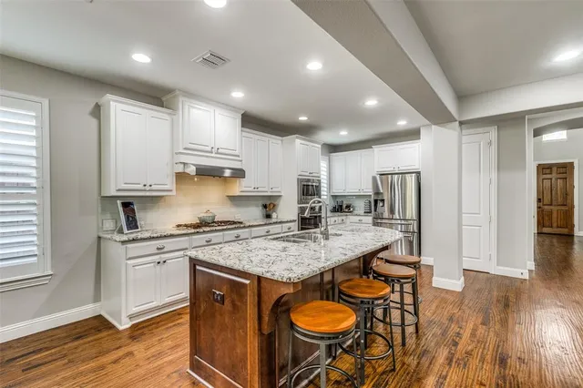 a kitchen with stainless steel appliances granite countertop a table chairs sink refrigerator and microwave
