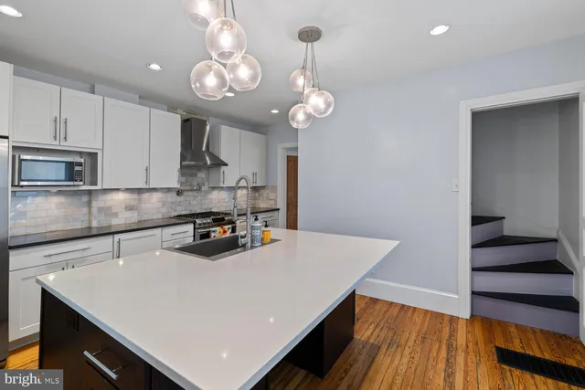 a kitchen with a appliances a chandelier and wooden floor