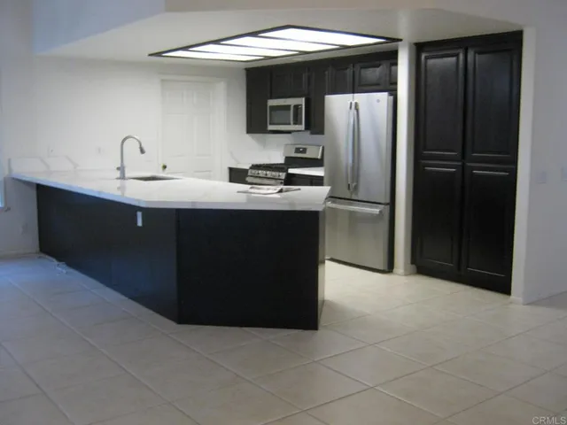 a kitchen with a sink a refrigerator and cabinets