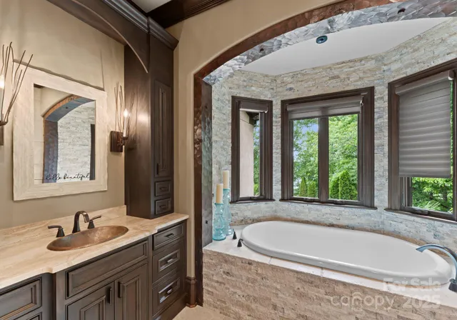 a bathroom with a granite countertop tub sink and mirror