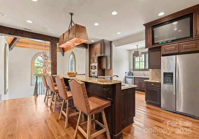 a kitchen with stainless steel appliances kitchen island granite countertop a table chairs and a refrigerator