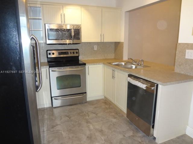 a kitchen with stainless steel appliances a stove microwave and sink