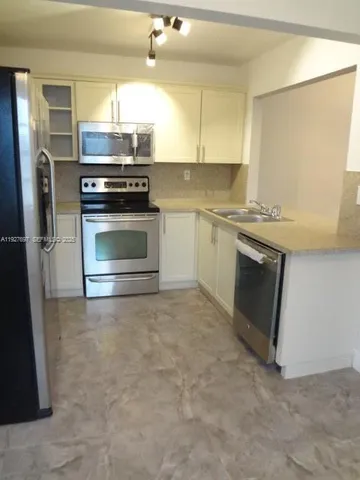 a kitchen with granite countertop a refrigerator and a stove top oven