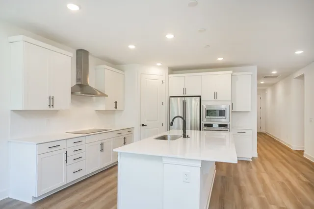 a large white kitchen with wooden floors and stainless steel appliances