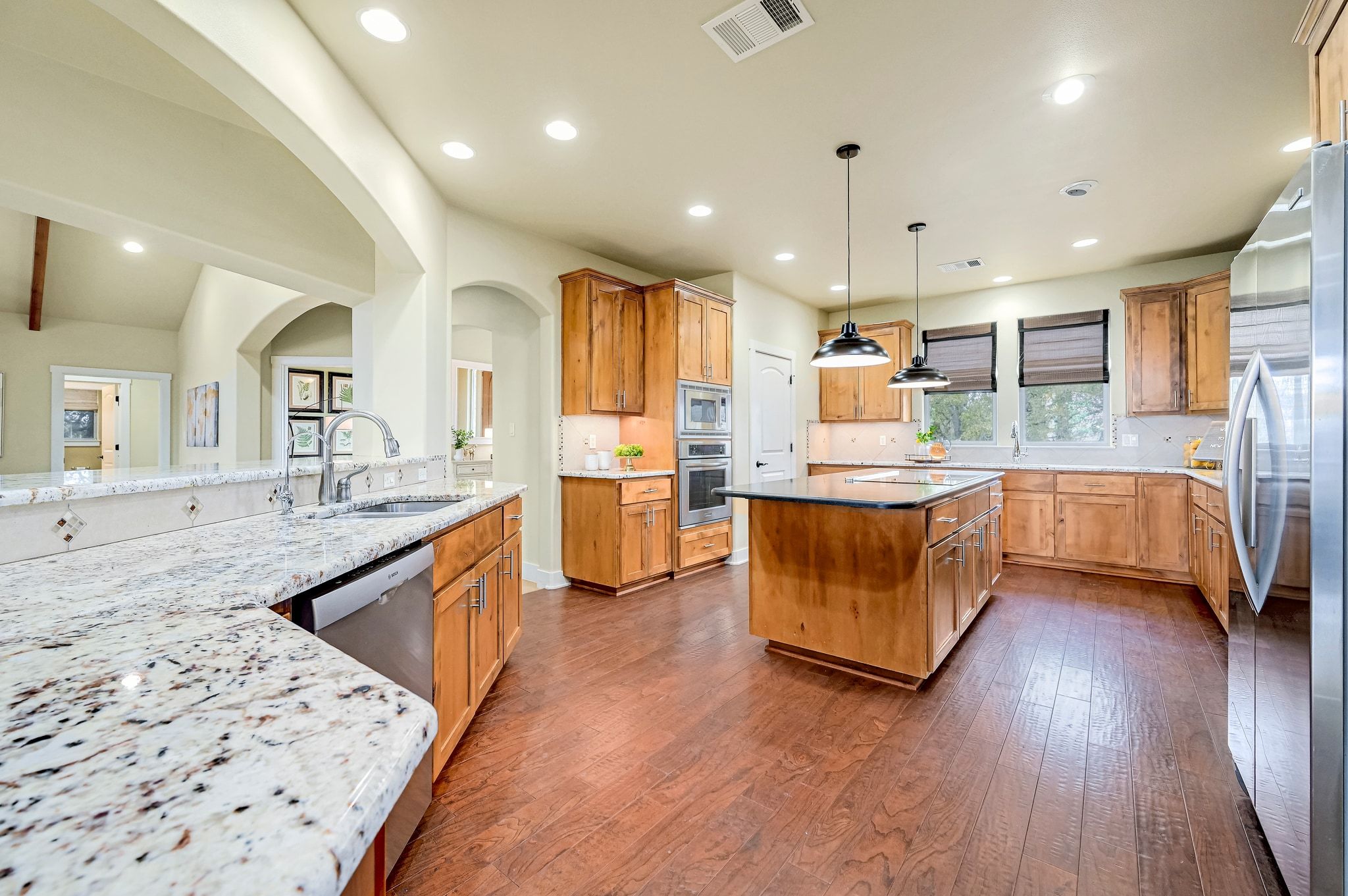 2551 Wolf Creek Ranch Road Burnet, TX 78611 - Photo 6 of 40 Kitchen with light stone counters, stainless steel appliances, pendant lighting, dark wood-type flooring, and a center island