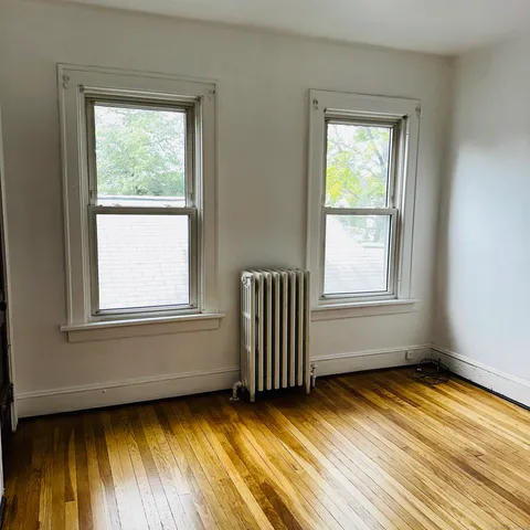 an empty room with a hardwood and windows